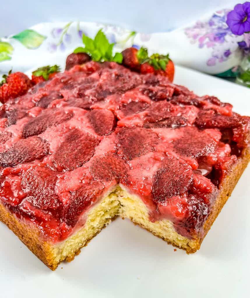 Strawberry Upside Down Cake on a plate with a slice cut out of it.