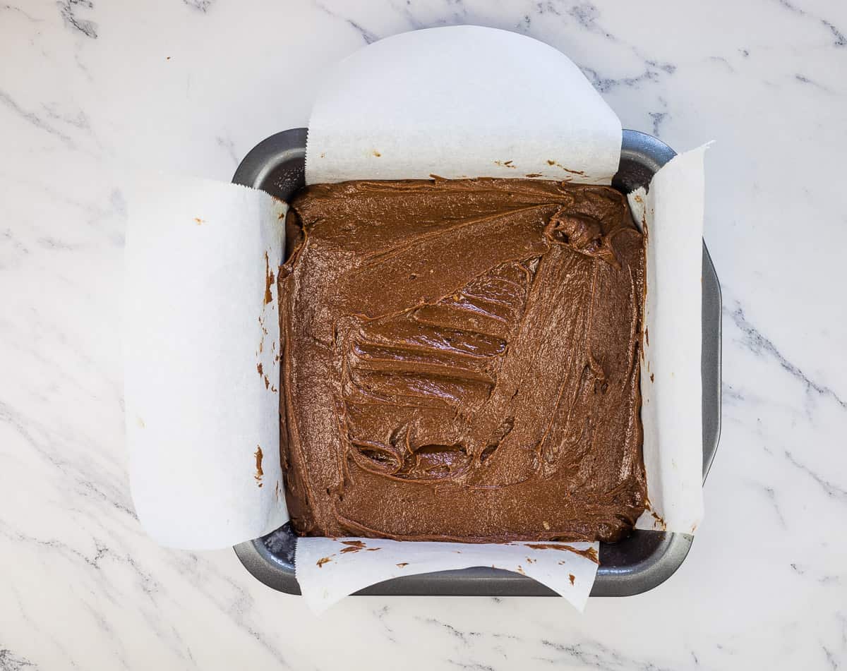 Brownie batter in a square pan.