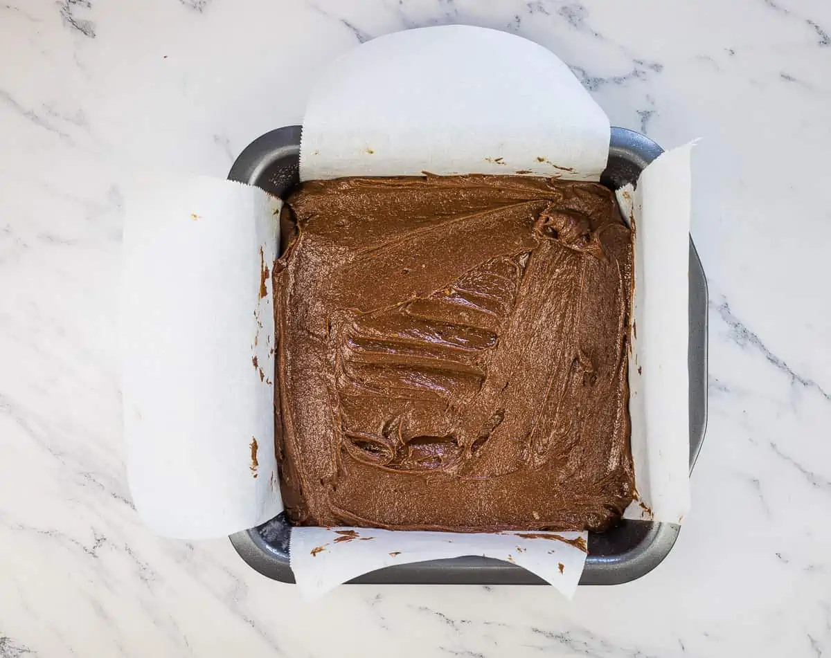 Brownie batter in a square pan.