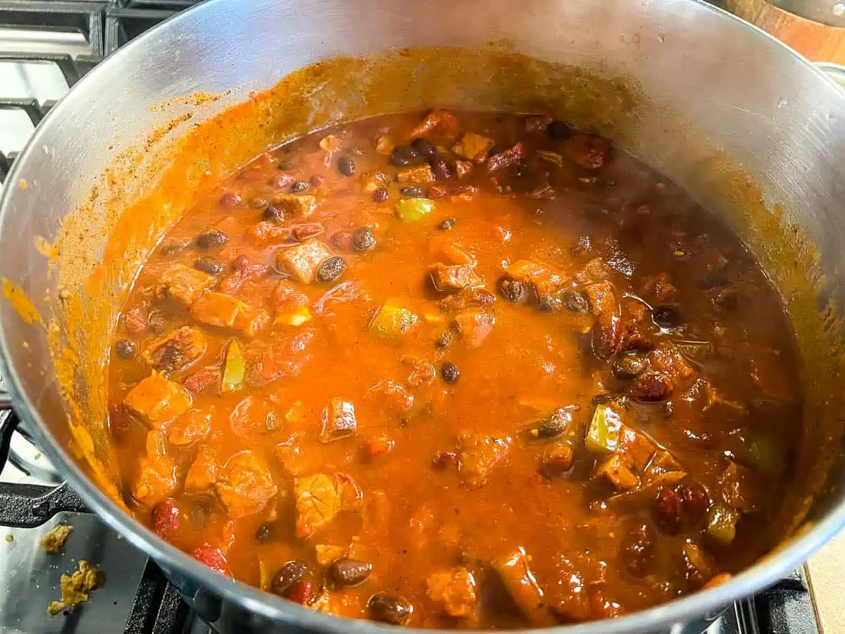 Adding the beans and masa after the brisket is tender.