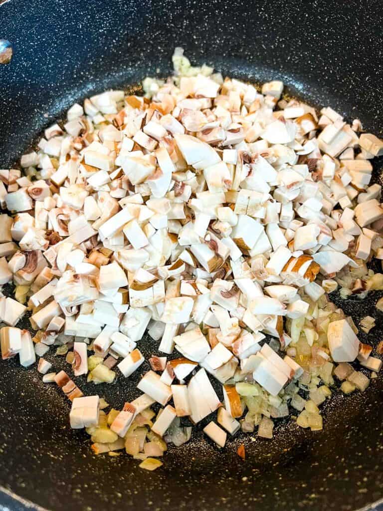 Adding the finely chopped mushrooms to the shallots.