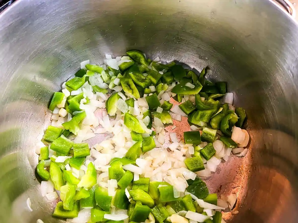 Onions, bell pepper and garlic cooking in a pot.