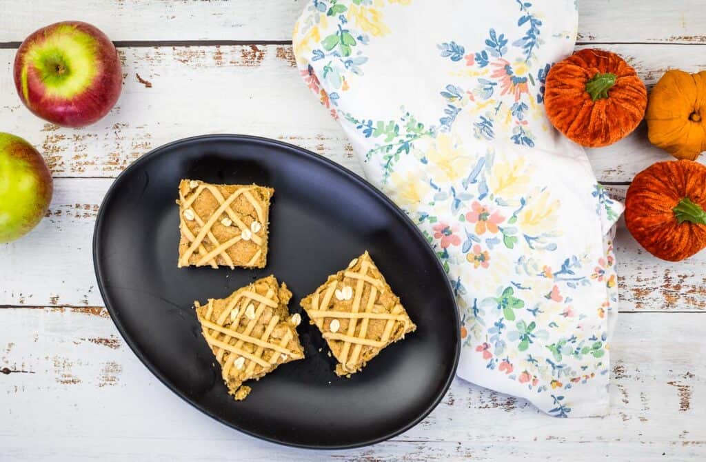 A top-down shot of 3 apple blondies on a black plate.