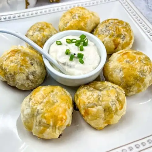 Beef Wellington Bites on a square plate with sauce in the middle.