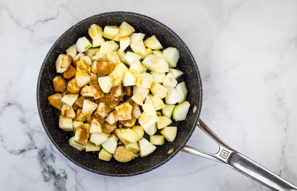Cooking the apples, butter, and sugar in a skillet.