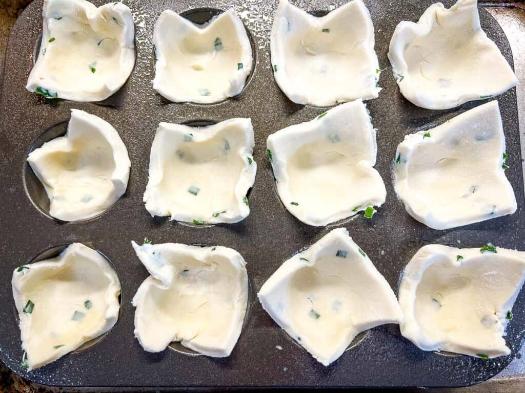 Squares of dough pressed into a mini muffin pan.