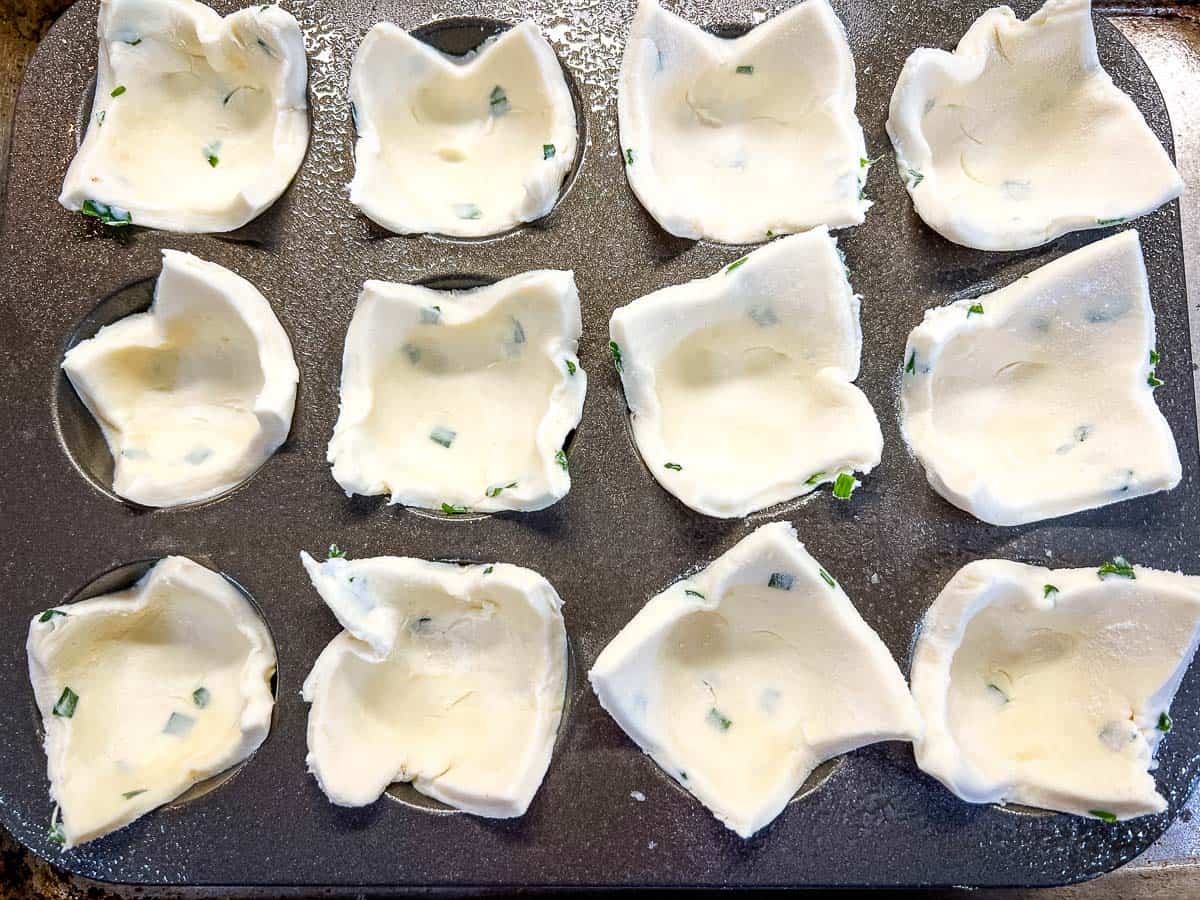 Squares of dough pressed into a mini muffin pan.
