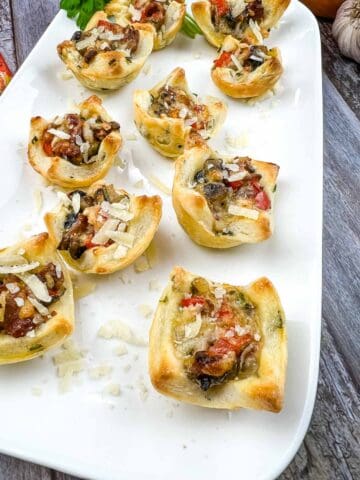 Bacon and mushroom tartlets on a white platter.