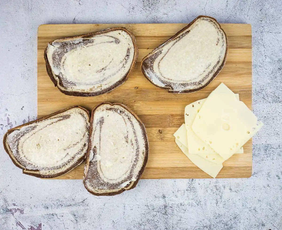 Buttered bread next to slices of cheese.