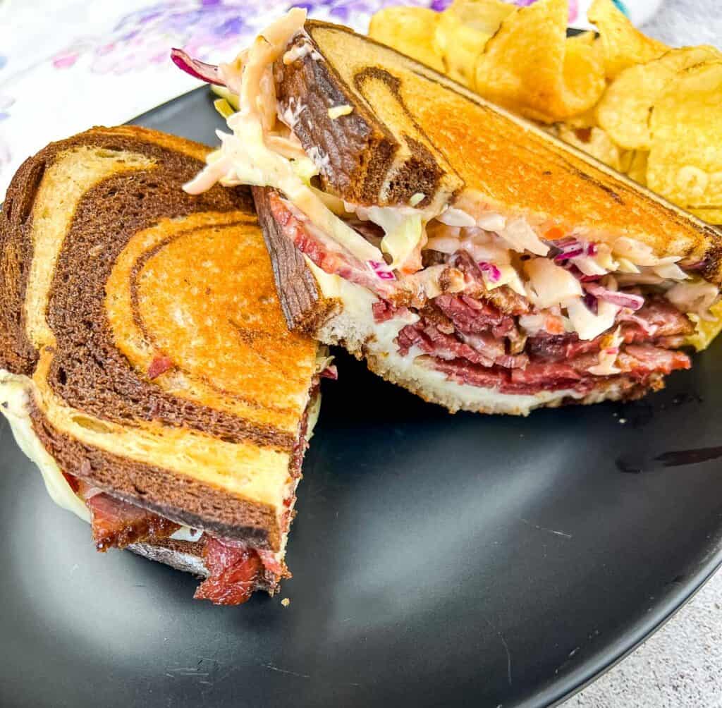Cut Rachel Sandwich on a plate with chips.