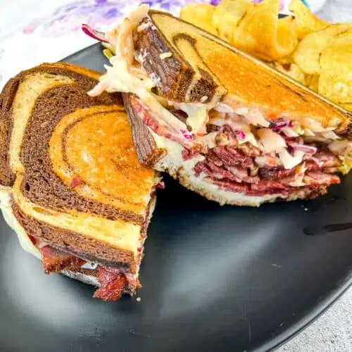 Cut Rachel Sandwich on a plate with chips.