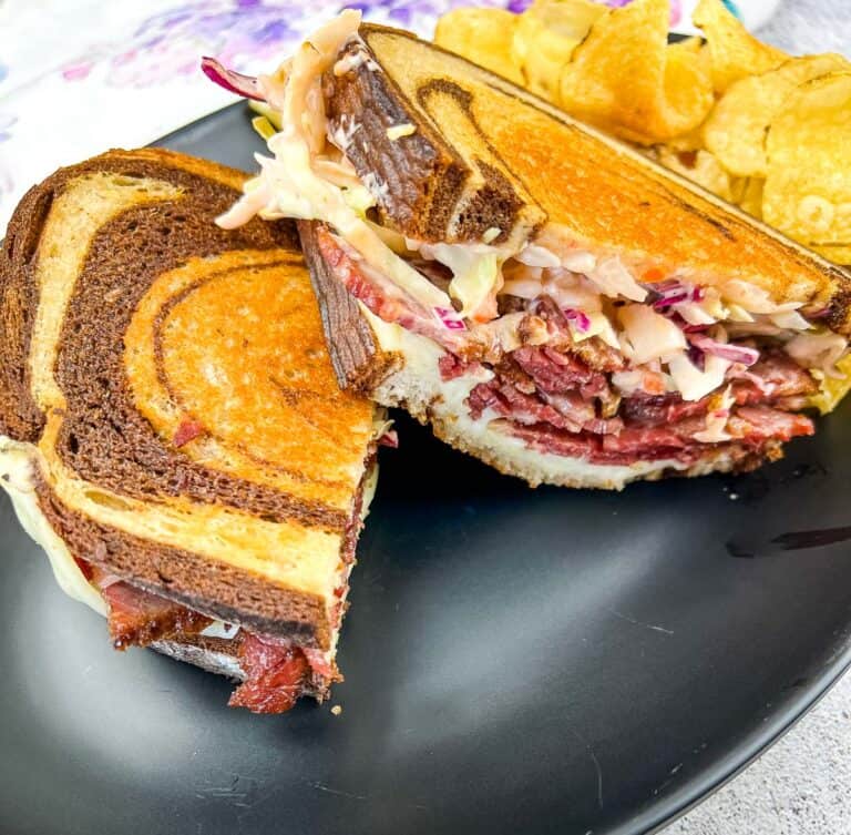 Cut Rachel Sandwich on a plate with chips.