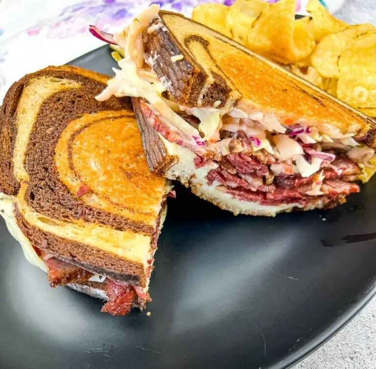 Cut Rachel Sandwich on a plate with chips.