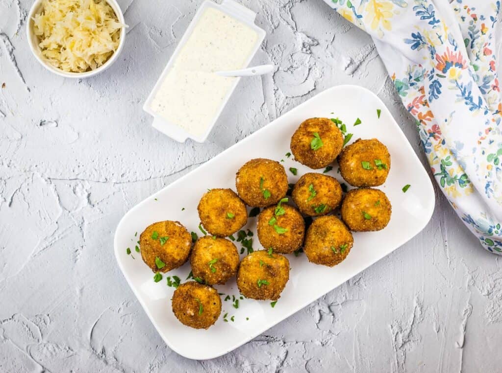 A top-down shot of Sauerkraut Balls with dipping sauce in a smaller dish.