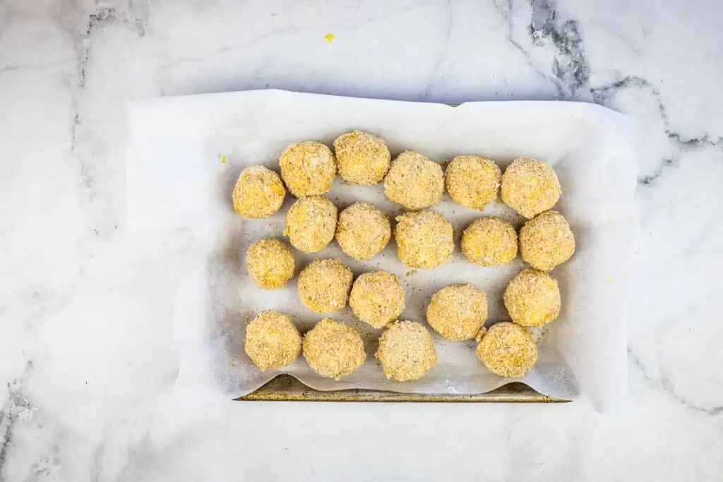Rolled and breaded sauerkraut balls on a small sheet pan.