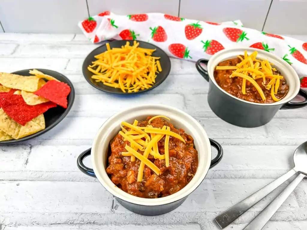 2 bowls of Smoked Brisket Chili on a table with tortilla chips in the background.