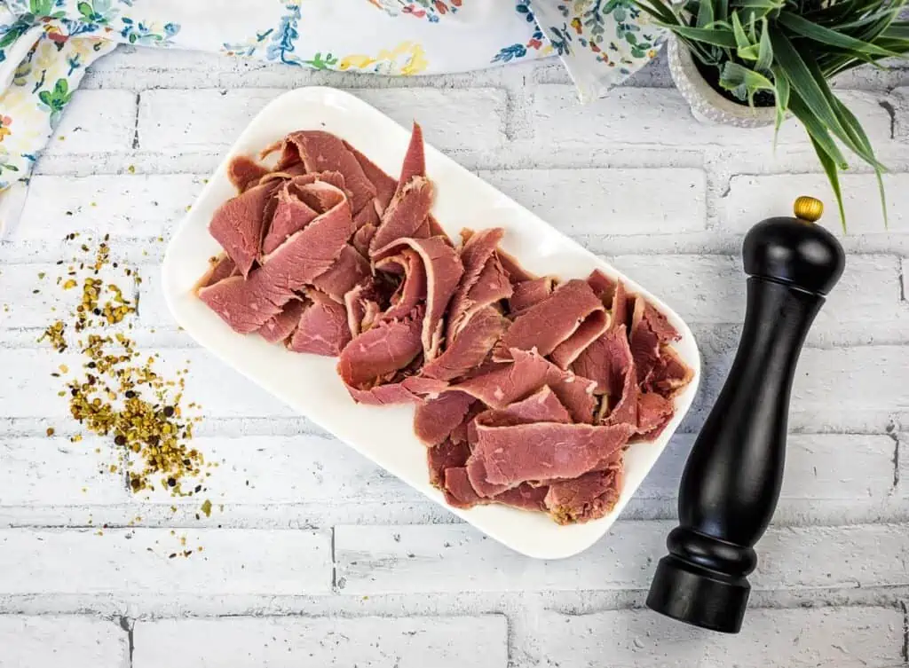 A top-down shot of sliced corned beef on a white platter.