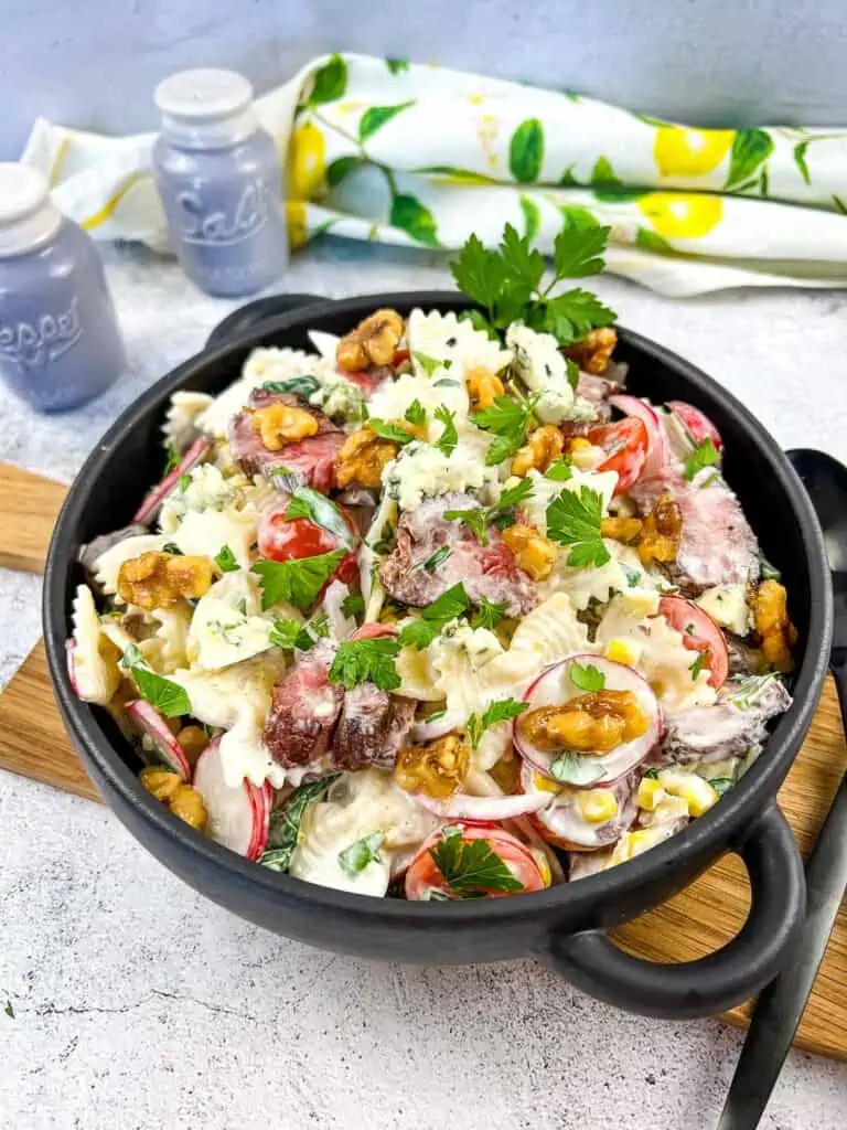 Steak and pasta salad in a black bowl.