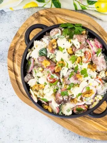 A top-down shot of steak and pasta salad in a black bowl.