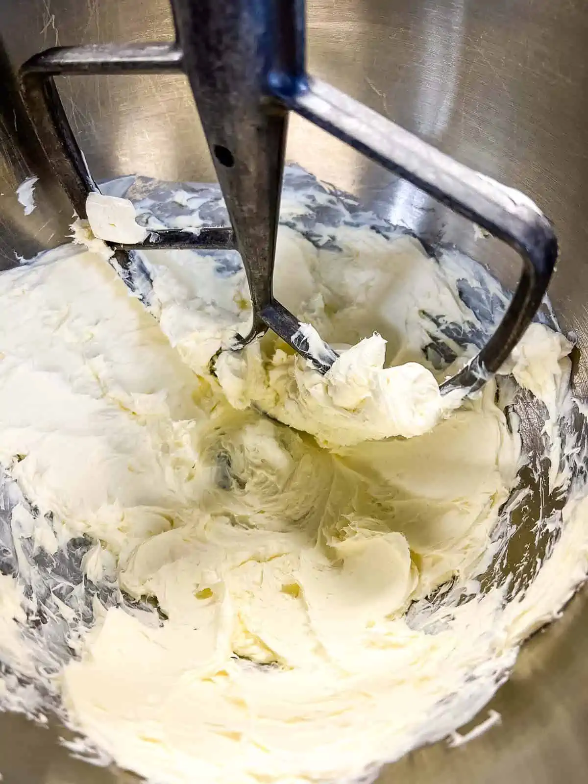 Whipped cream cheese in the bowl of a stand mixer.