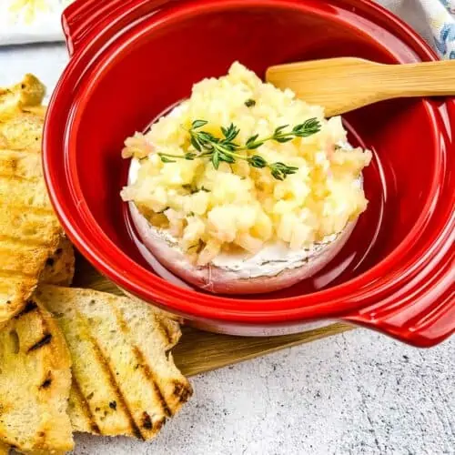 Baked Brie with Apple Ginger Chutney in a red brie baker with bread on the side.