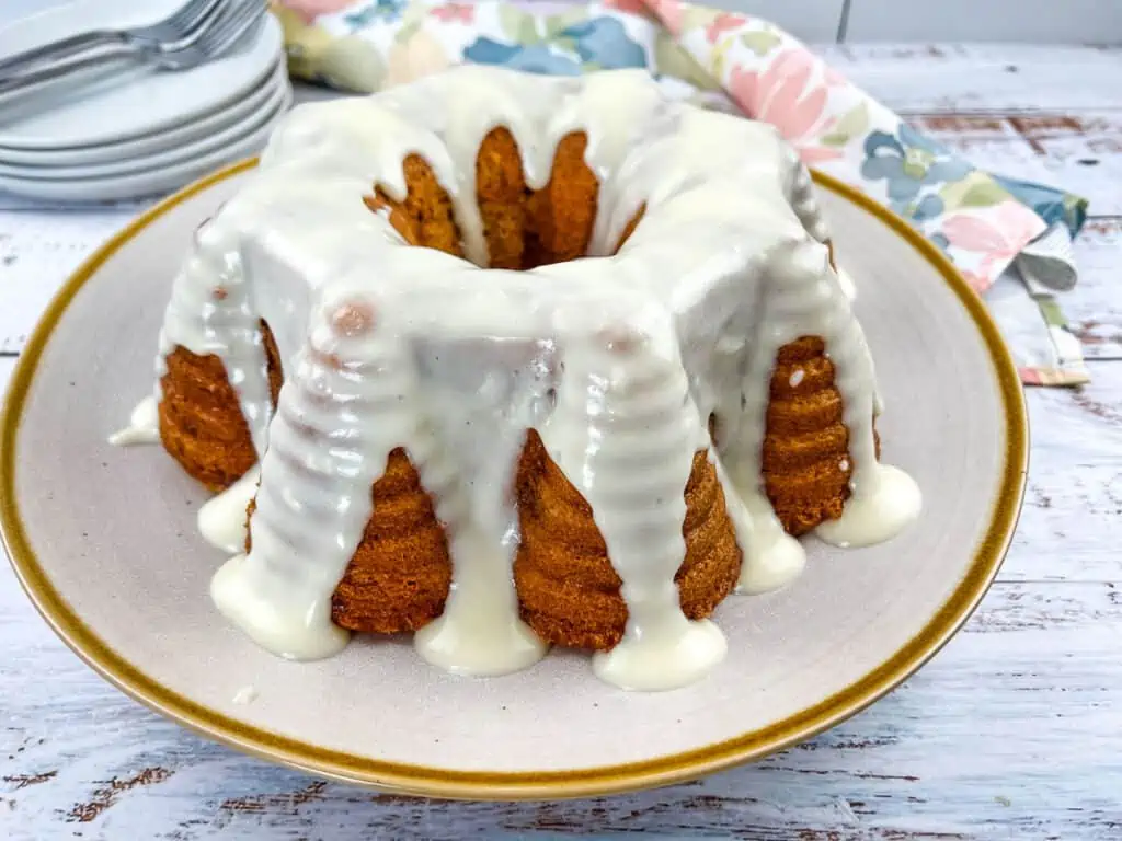 A whole Buttermilk Banana Cake with Cream Cheese Glaze on a large plate.