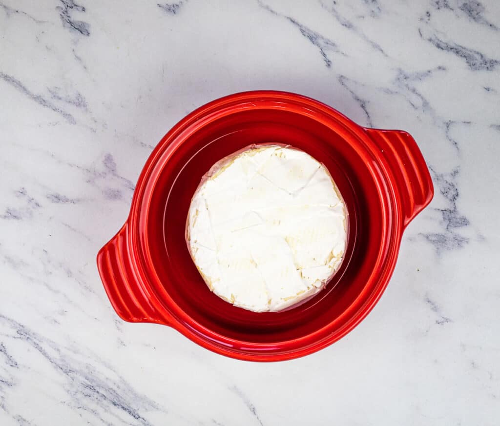 A wheel of brie in a brie baker dish.