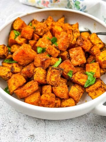 Air fryer sweet potato cubes in a white serving dish.