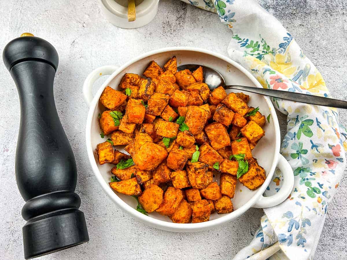 A closeup of Air Fryer Sweet Potato Cubes in a white serving dish.