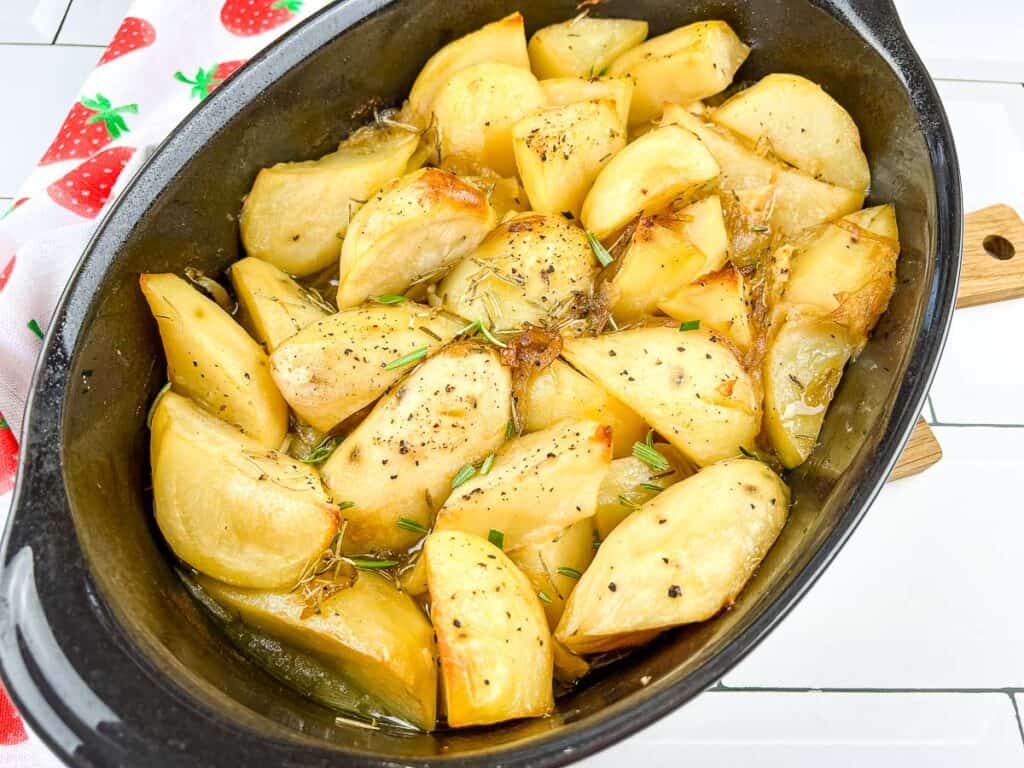 Garlic and rosemary braised potatoes in a baking dish.
