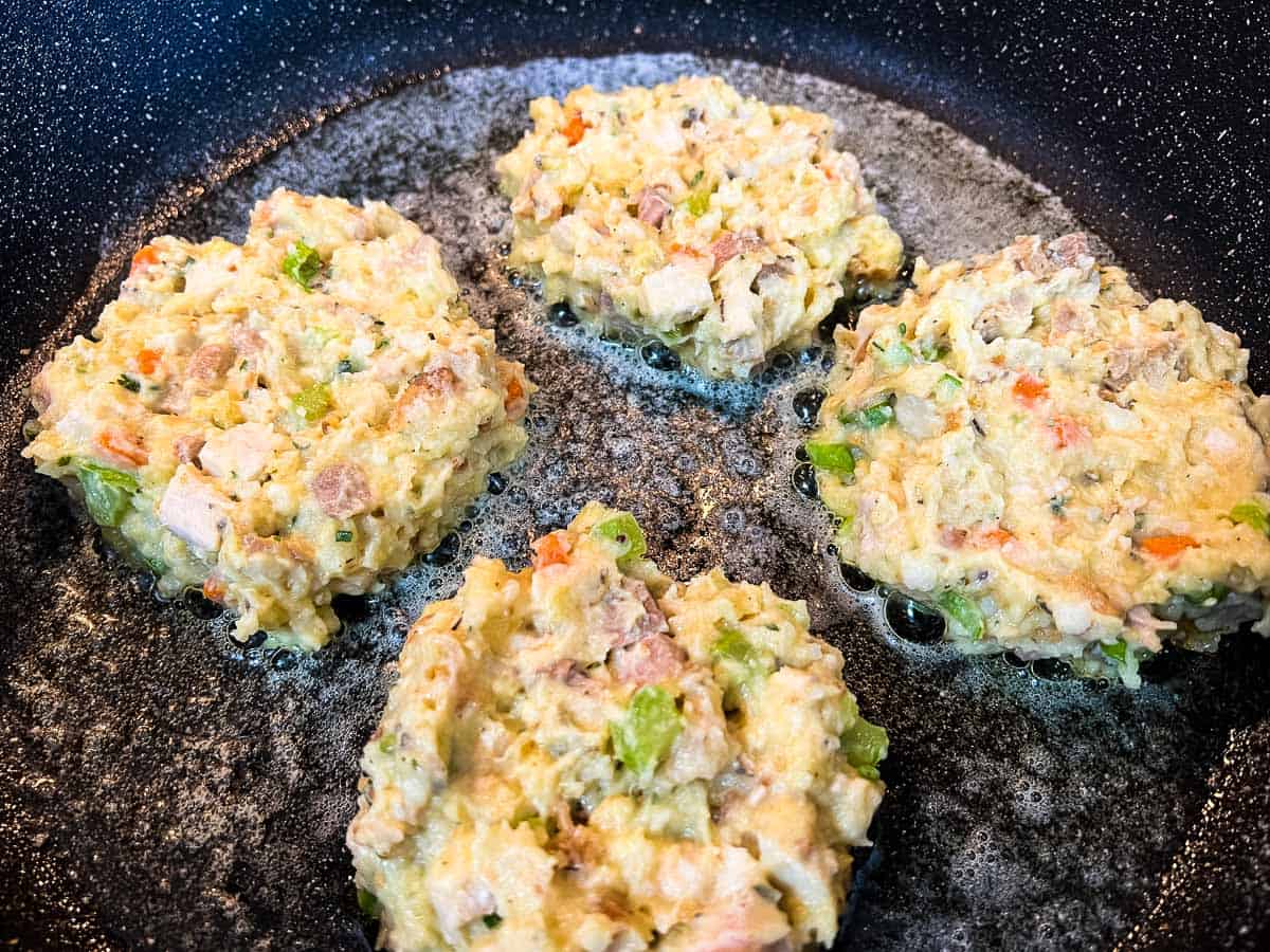 The balls pressed into patties in a skillet.