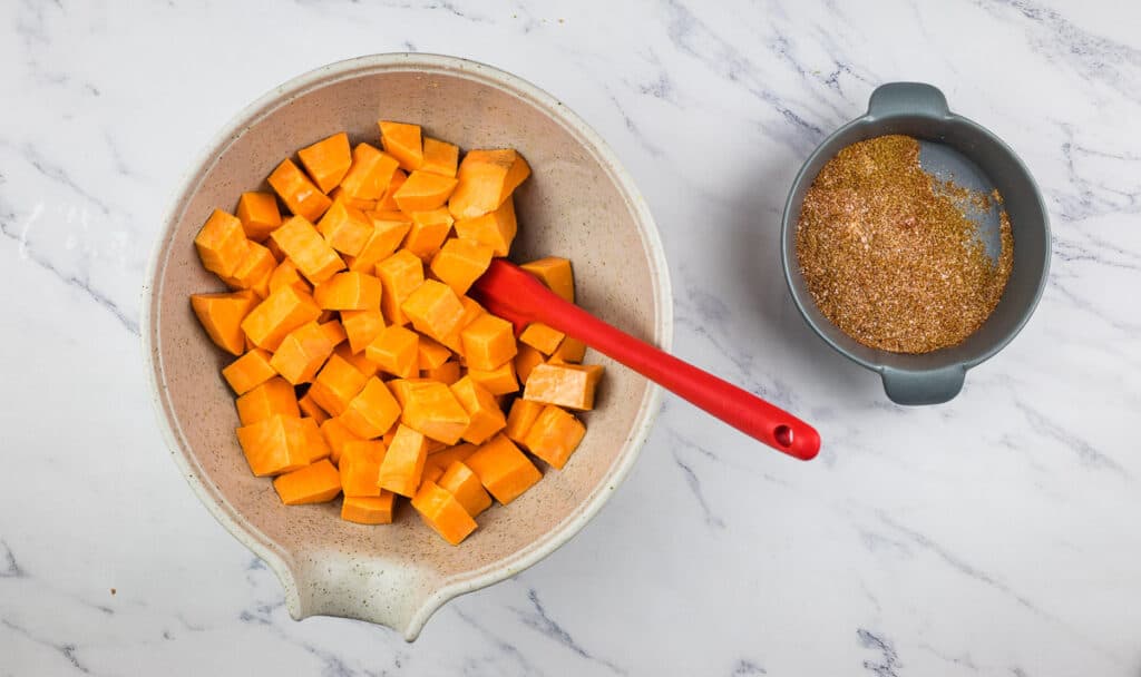 Mixing the sweet potato cubes with the oil and spices.