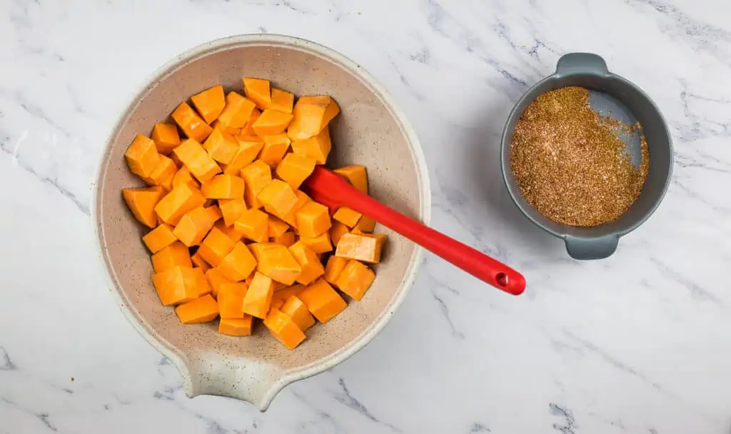 Mixing the sweet potato cubes with the oil and spices.