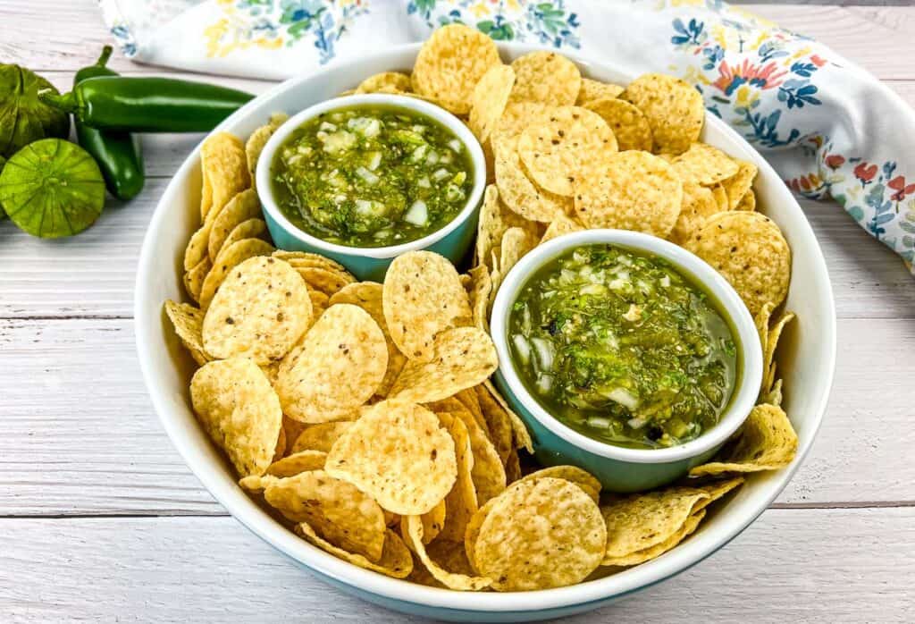 A top-down shot of Roasted Tomatillo Salsa in a serving dish with tortilla chips.