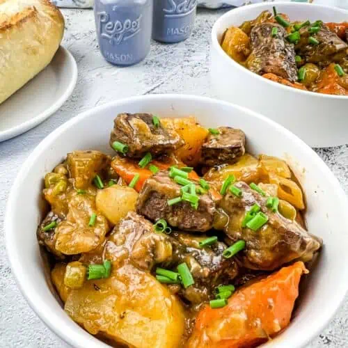 Smoked beef stew in a white bowl with a second bowl in the background.