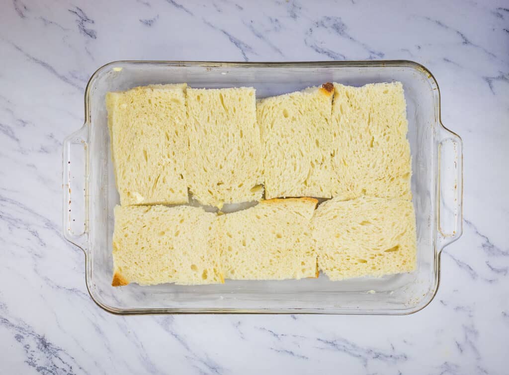 Bread layered in the bottom of a baking dish.