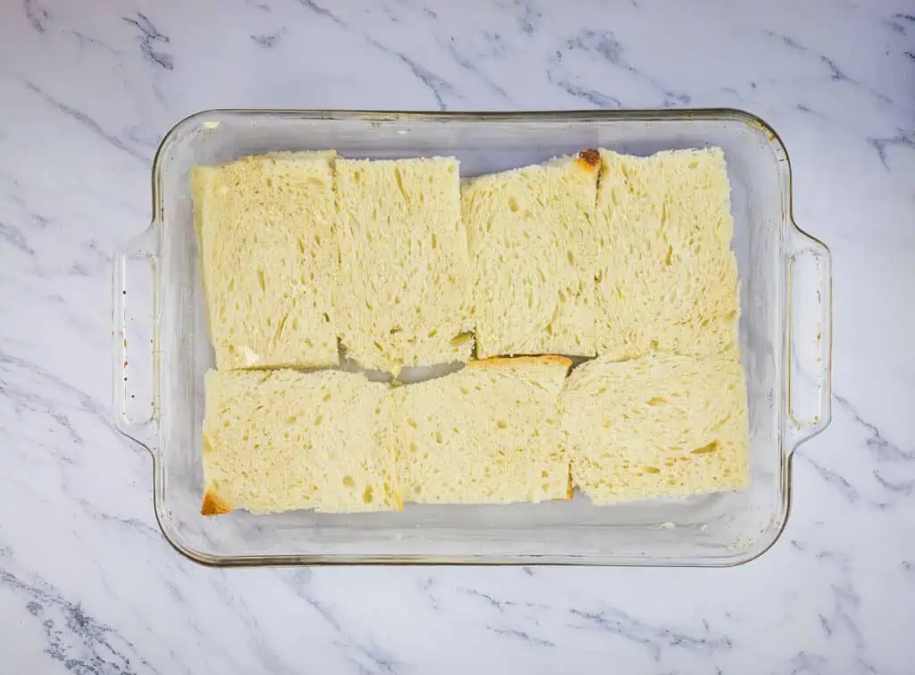 Bread layered in the bottom of a baking dish.
