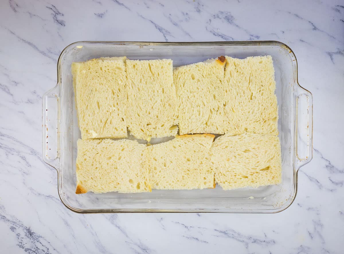 Bread layered in the bottom of a baking dish.