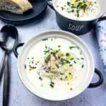 Two black bowls of Cullen Skink with bread in the background.