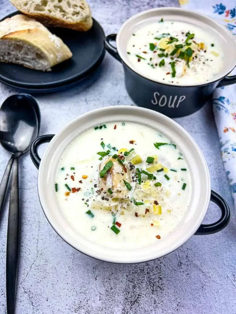 Two black bowls of Cullen Skink with bread in the background.