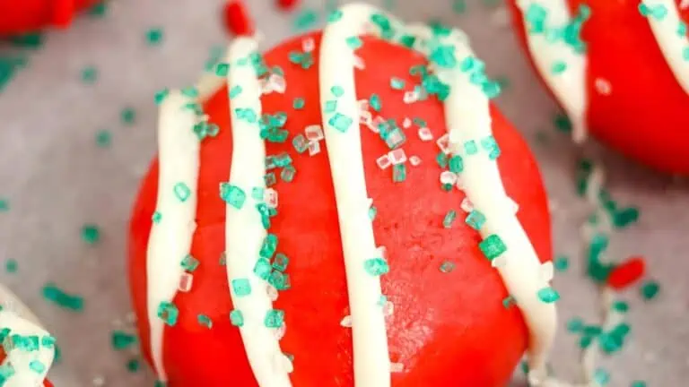 A plate of red velvet truffles covered in sprinkles.
