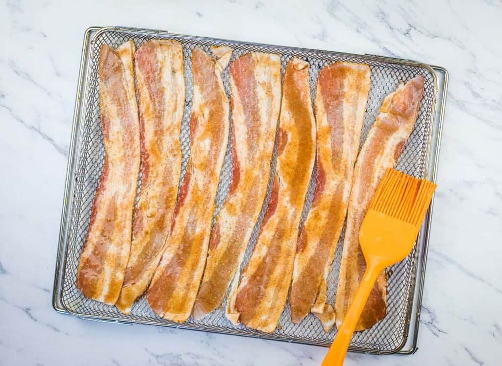 Brushing the bacon with the sugary glaze.