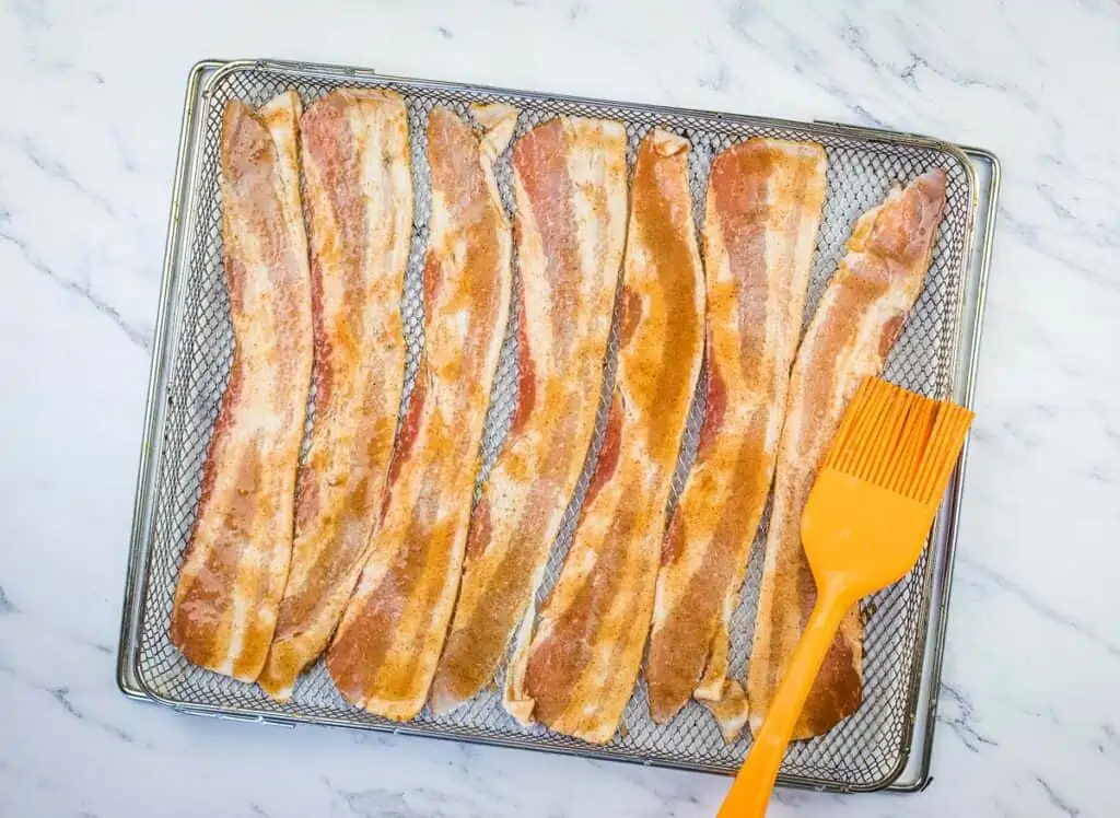 Brushing the bacon with the sugary glaze.