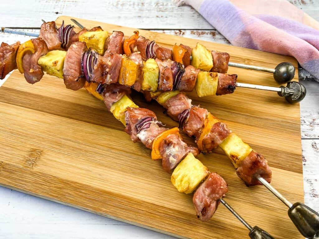 Smoked pork and pineapple skewers on a board.