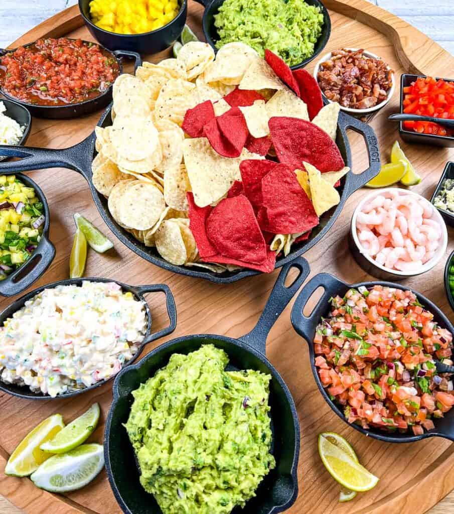A guacamole snack board loaded with dips, salsas, chips and more.