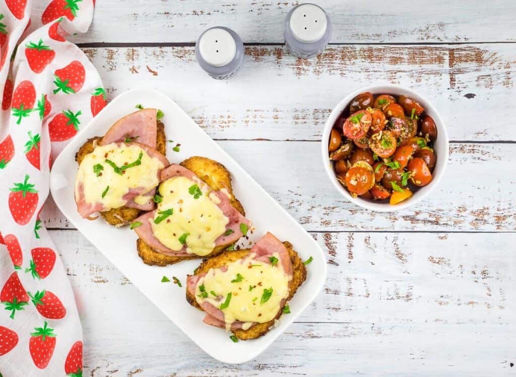 A top down shot of air fryer chicken cordon bleu with tomato salad in a bowl nearby.