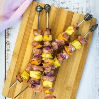 Smoked pork & pineapple skewers on a wooden board.