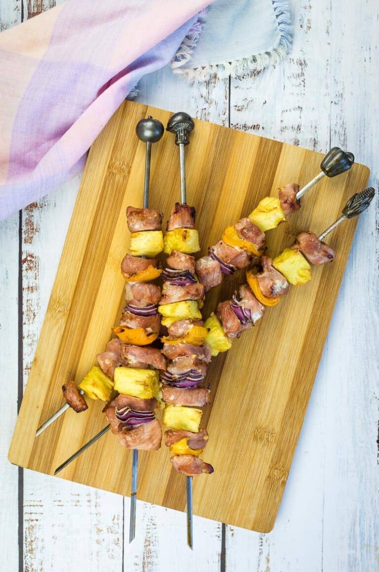 Smoked pork & pineapple skewers on a wooden board.