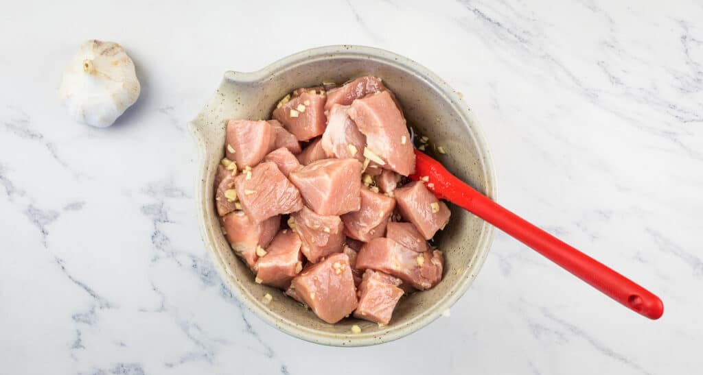 Pork and marinade in a bowl.