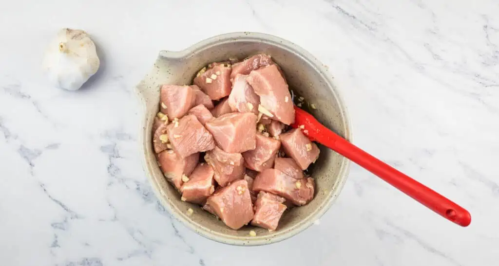 Pork and marinade in a bowl.